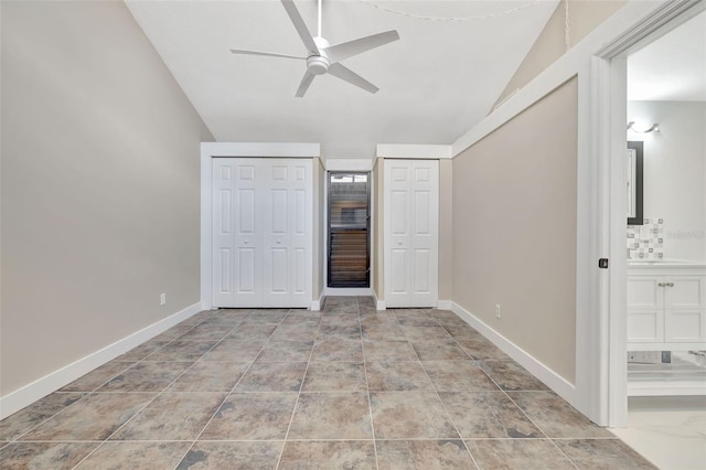 unfurnished bedroom with ceiling fan, vaulted ceiling, multiple closets, and ensuite bathroom