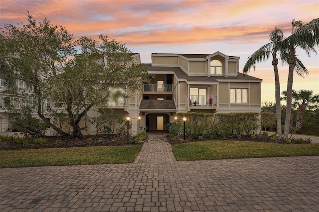 view of front of house featuring a balcony and a lawn