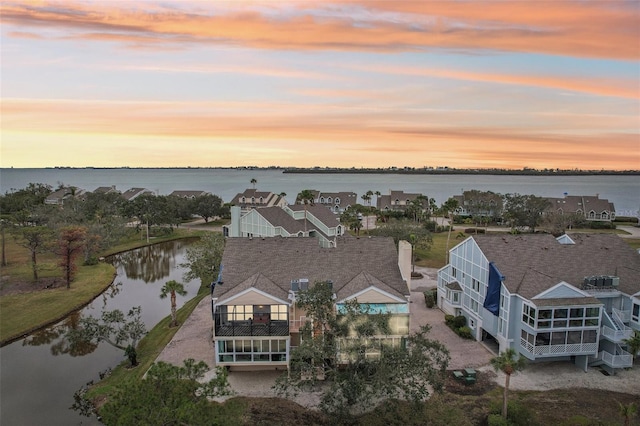 aerial view at dusk featuring a water view