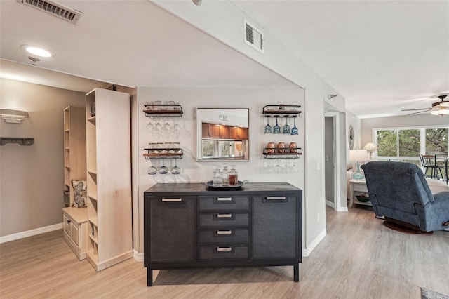 bar featuring ceiling fan, dark brown cabinetry, and light wood-type flooring