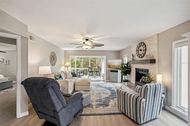 living room with ceiling fan, a fireplace, and light wood-type flooring