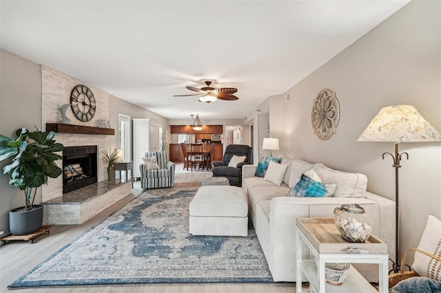 living room featuring ceiling fan, hardwood / wood-style floors, and a fireplace