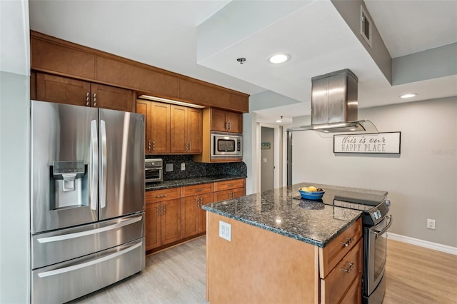 kitchen with island range hood, dark stone counters, a kitchen island, stainless steel appliances, and decorative backsplash