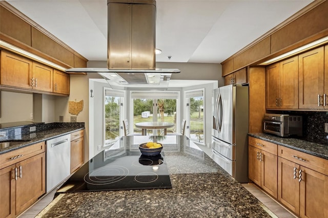 kitchen with dark stone countertops, decorative backsplash, stainless steel appliances, and island exhaust hood