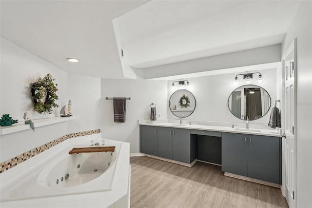 bathroom featuring vanity, tiled bath, and hardwood / wood-style floors