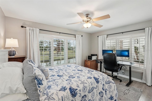 bedroom with ceiling fan, wood-type flooring, and multiple windows