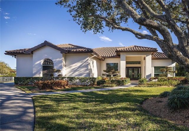 mediterranean / spanish home with french doors and a front lawn