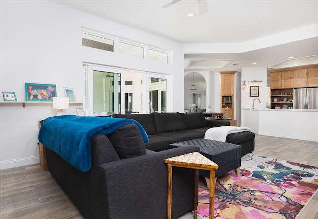 living room with ceiling fan, sink, and light hardwood / wood-style floors