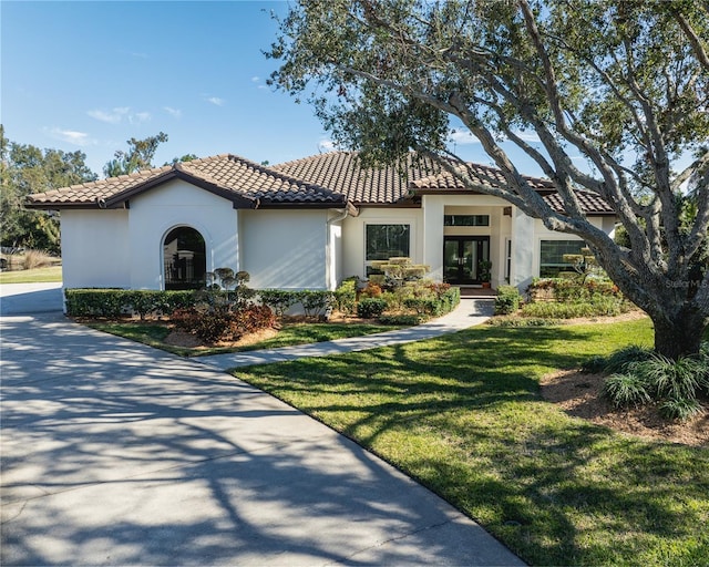 mediterranean / spanish-style home with french doors and a front lawn