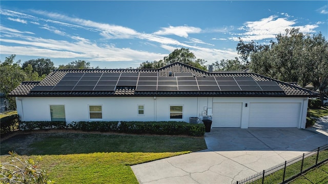 view of side of home with a garage, a yard, central air condition unit, and solar panels