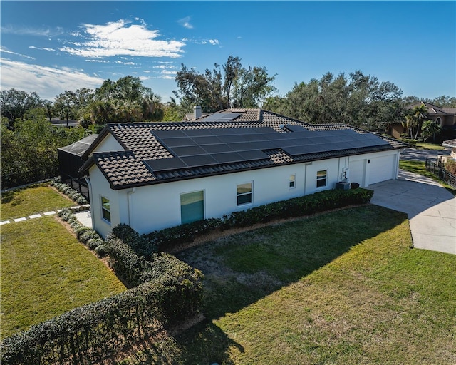 view of side of home with a garage, a yard, central AC, and solar panels