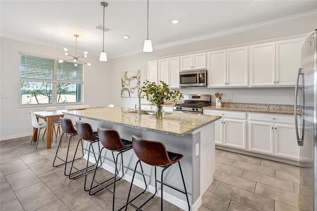 kitchen with white cabinetry, appliances with stainless steel finishes, an island with sink, and hanging light fixtures