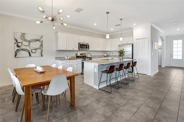 kitchen featuring sink, white cabinetry, light stone counters, an island with sink, and stainless steel appliances