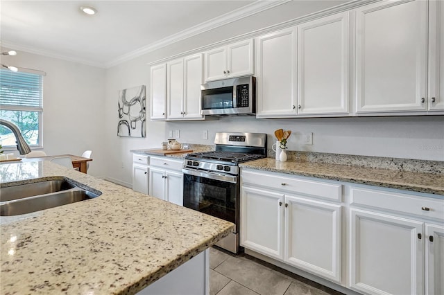 kitchen featuring appliances with stainless steel finishes, sink, white cabinets, crown molding, and light stone countertops