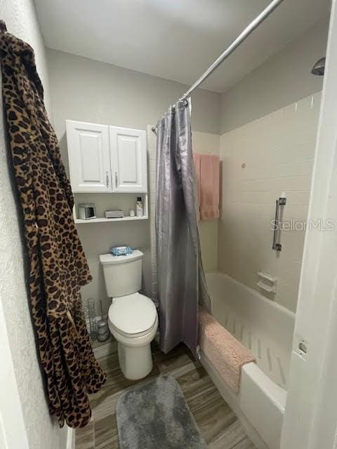 bathroom featuring hardwood / wood-style flooring, shower / bath combination with curtain, and toilet