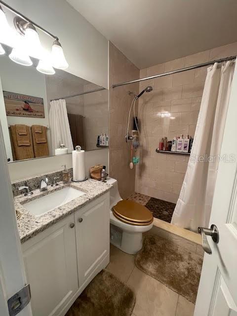 bathroom featuring tile patterned flooring, vanity, curtained shower, and toilet