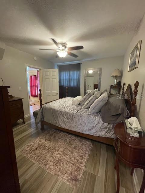 bedroom with ceiling fan, hardwood / wood-style flooring, and a textured ceiling