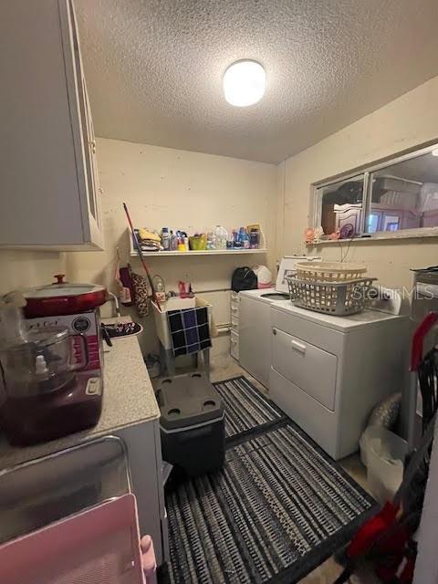 washroom with washer and clothes dryer, cabinets, and a textured ceiling