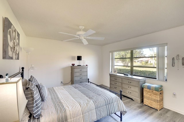 bedroom featuring ceiling fan, light hardwood / wood-style floors, and a textured ceiling