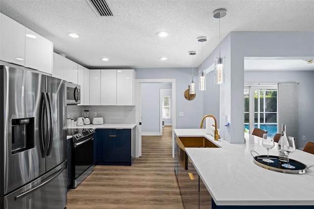 kitchen featuring pendant lighting, dark hardwood / wood-style flooring, white cabinets, and appliances with stainless steel finishes