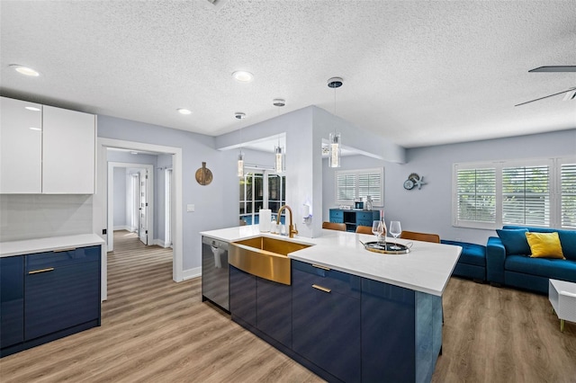 kitchen with pendant lighting, light hardwood / wood-style flooring, dishwasher, white cabinetry, and a center island with sink