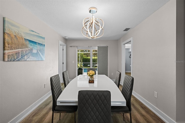 dining room featuring dark hardwood / wood-style flooring, a textured ceiling, and a notable chandelier