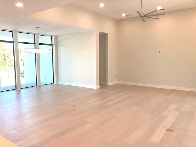 unfurnished room featuring a wall of windows, ceiling fan, and light wood-type flooring