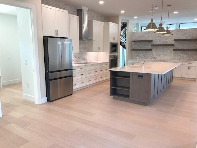 kitchen featuring white cabinets, wall chimney exhaust hood, stainless steel appliances, light countertops, and open shelves