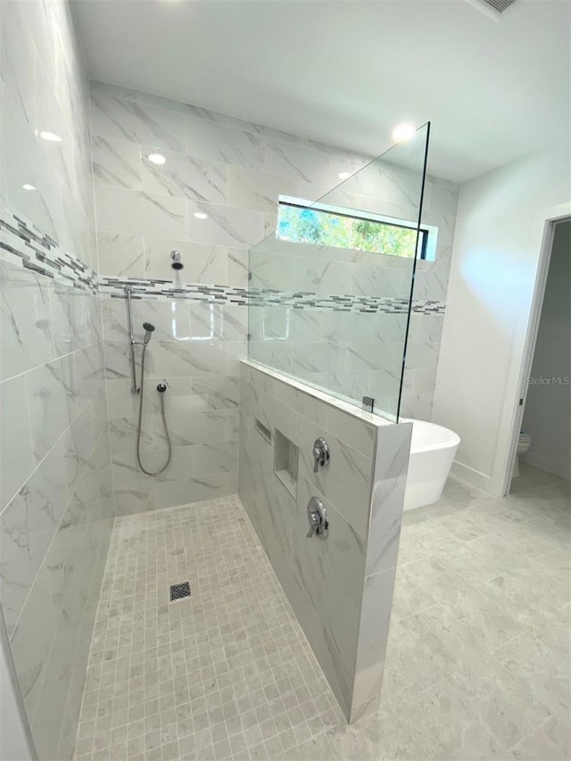 bathroom with a soaking tub, a marble finish shower, and baseboards