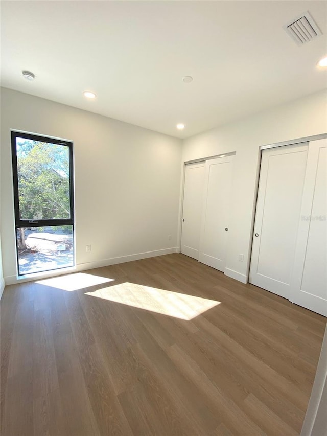 unfurnished bedroom with two closets and dark hardwood / wood-style floors