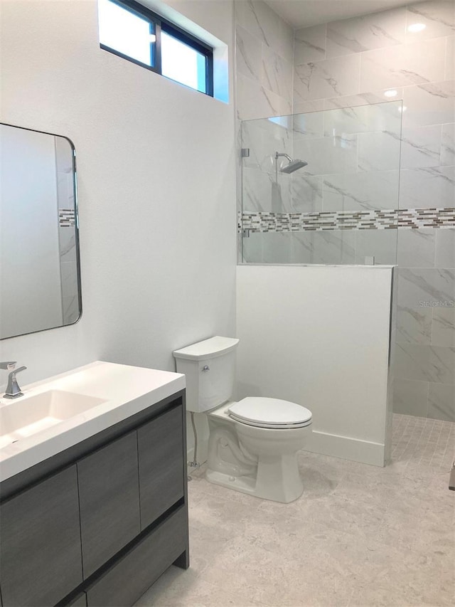 bathroom featuring vanity, tiled shower, and toilet