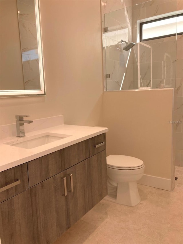 bathroom with vanity, toilet, and a tile shower