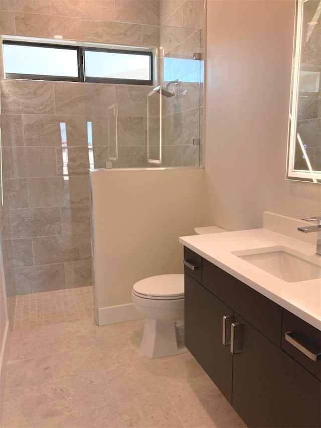 bathroom with vanity, tiled shower, and toilet