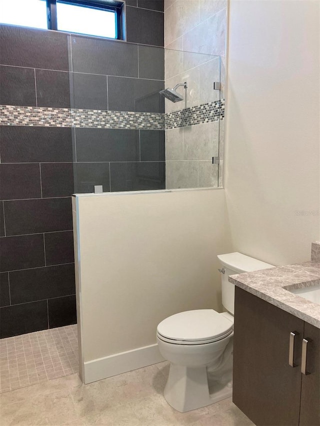 bathroom with vanity, toilet, and a tile shower