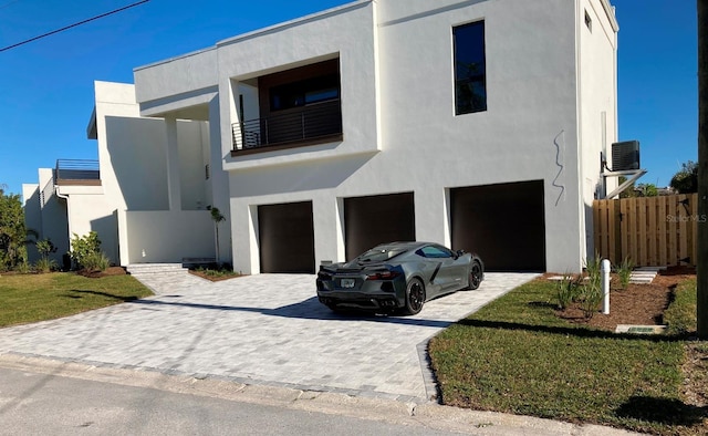 contemporary house with a balcony, a garage, and a front yard