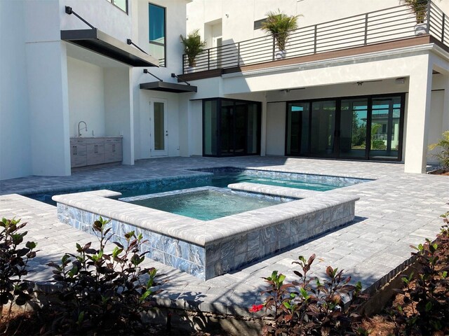 view of pool featuring an in ground hot tub, an outdoor kitchen, sink, and a patio area