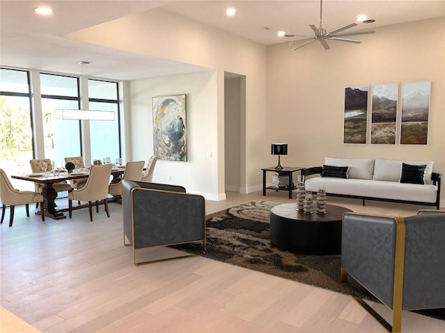 living room featuring light wood-type flooring, floor to ceiling windows, baseboards, and recessed lighting