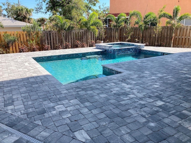 view of pool featuring a fenced backyard, a pool with connected hot tub, and a patio