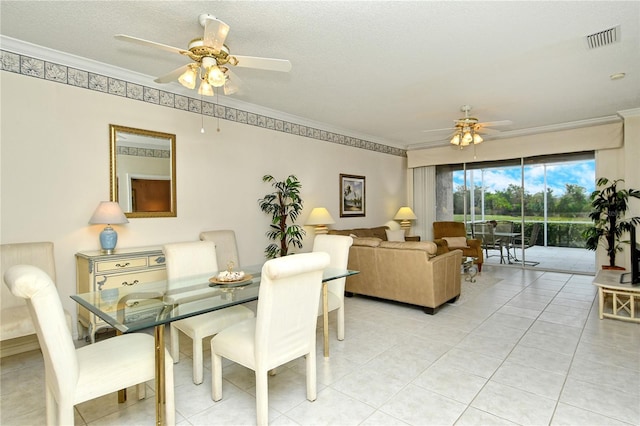 tiled dining space featuring ornamental molding, a textured ceiling, and ceiling fan