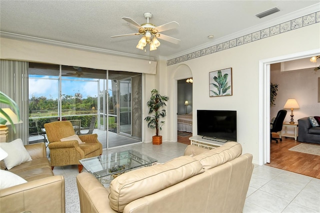 tiled living room with crown molding, ceiling fan, and a textured ceiling