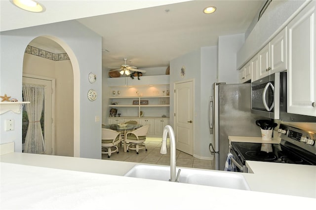 kitchen featuring appliances with stainless steel finishes, sink, white cabinets, light tile patterned floors, and ceiling fan