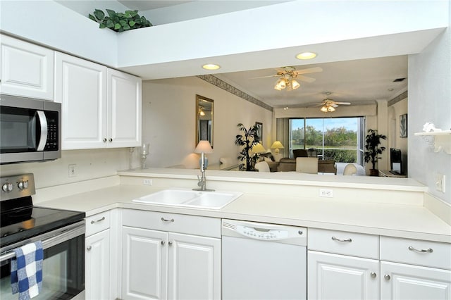 kitchen with appliances with stainless steel finishes, kitchen peninsula, sink, and white cabinets