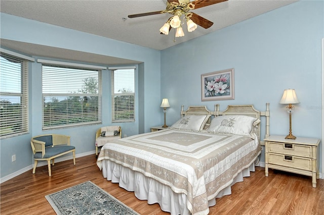 bedroom featuring ceiling fan, wood-type flooring, and a textured ceiling