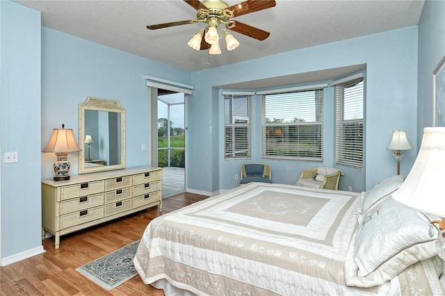 bedroom with hardwood / wood-style floors, ceiling fan, access to outside, and a textured ceiling