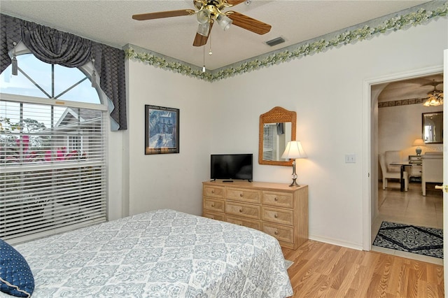 bedroom with ceiling fan, a textured ceiling, and light hardwood / wood-style flooring