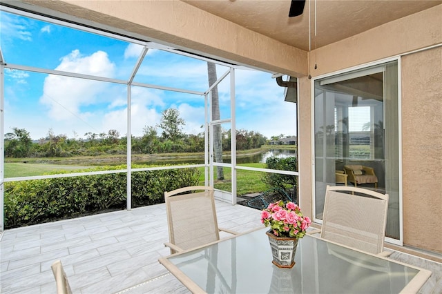 sunroom / solarium with a water view and ceiling fan