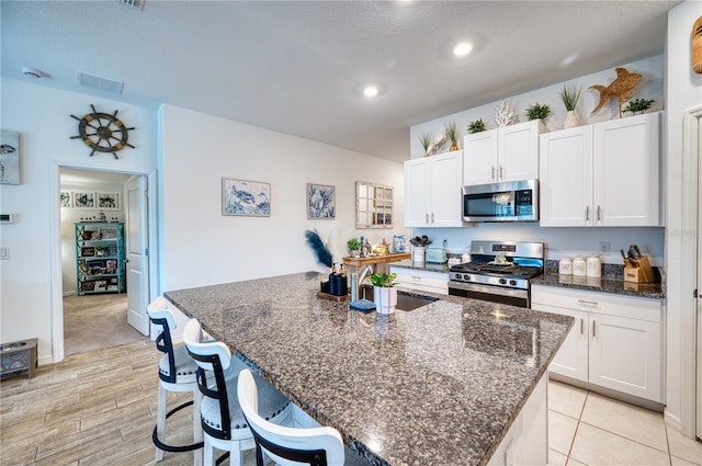 kitchen featuring stainless steel appliances, white cabinetry, a kitchen island with sink, and sink