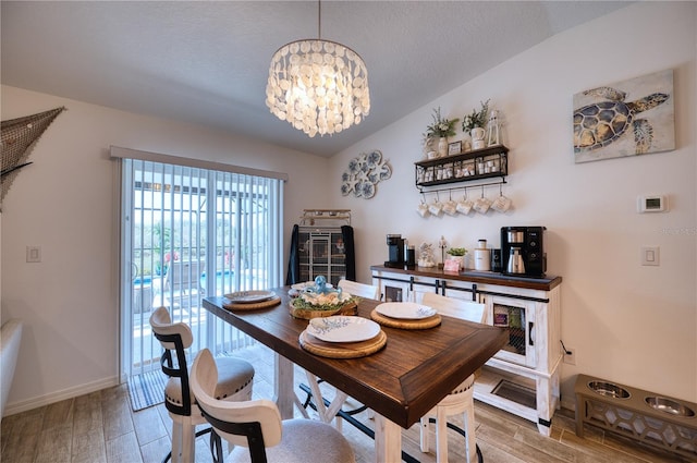 dining area with lofted ceiling, hardwood / wood-style floors, a textured ceiling, and a chandelier