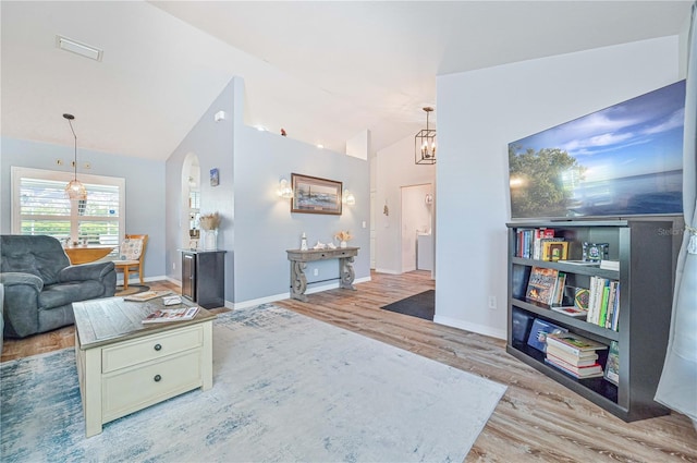 living room featuring light hardwood / wood-style flooring, vaulted ceiling, and an inviting chandelier