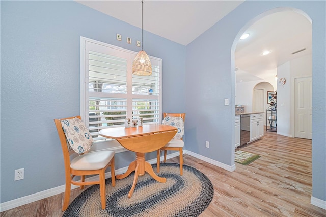 dining area featuring vaulted ceiling and light hardwood / wood-style flooring